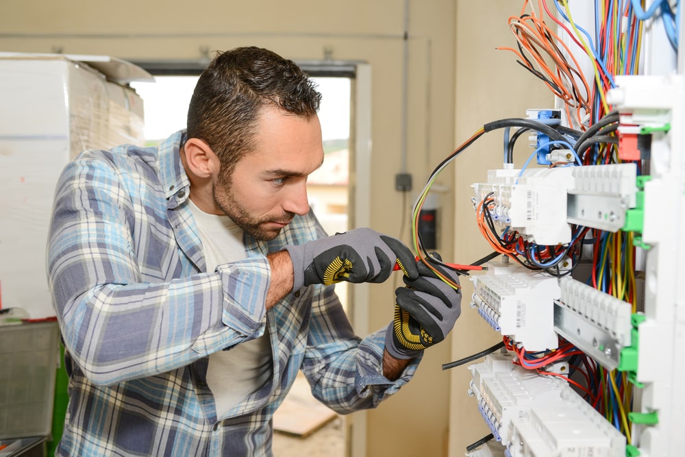 An electrician safely fixing a wiring issue inside a building.