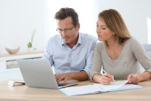 Small Loans Banner - Middle-aged couple comparing payday loan interest rates on a laptop
