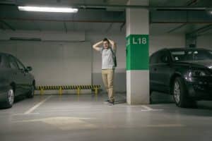 Car Insurance Banner - Young man with hands on his head standing in a carpark after his car is stolen